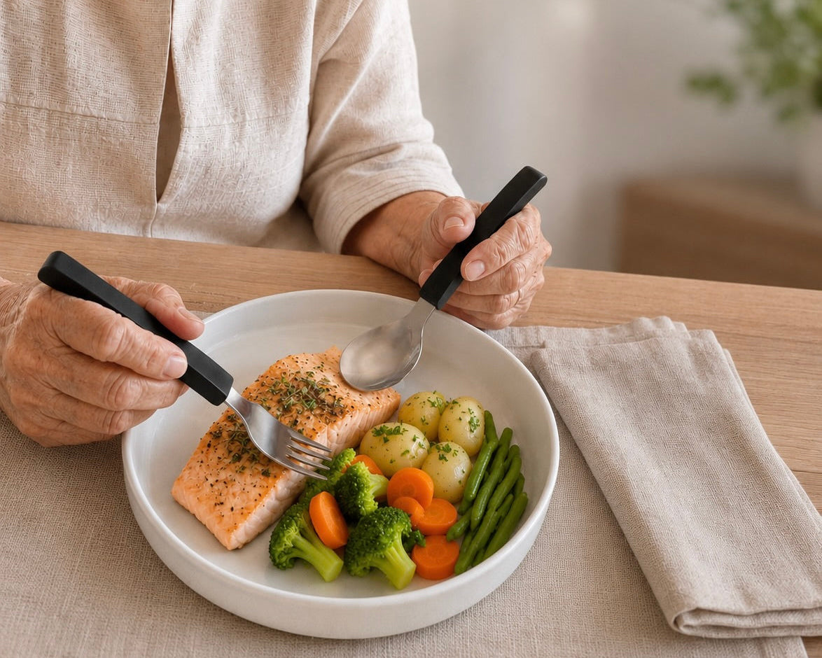 Person eating a meal with salmon, vegetables, and potatoes at a table.